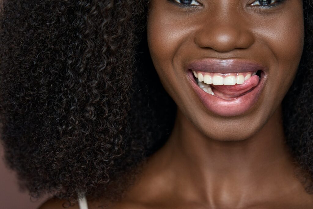 Happy black young woman smiling with dental smile advertising white teeth.