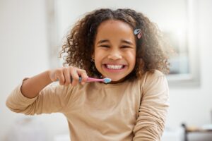 Portrait of an adorable little girl brushing her teeth in a bathroom at home