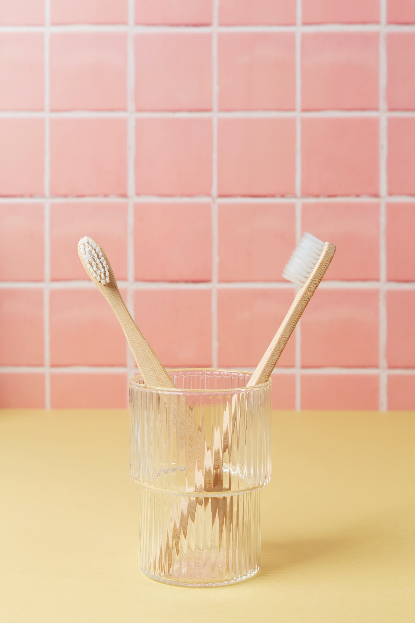 Natural bamboo eco friendly toothbrushes in a glass on table inside a bathroom