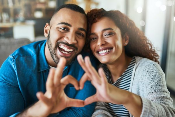 Shot of a young couple making a heart gesture with their hands outdoors
